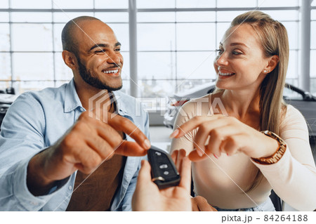 Cheerful couple taking keys of their new car in car dealership 84264188