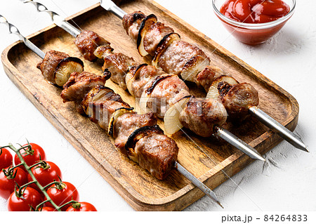Shish kebab BBQ meat with onions and tomatoes, on white stone table background Shish kebab BBQ meat with onions and tomatoes, on white stone table background 84264833