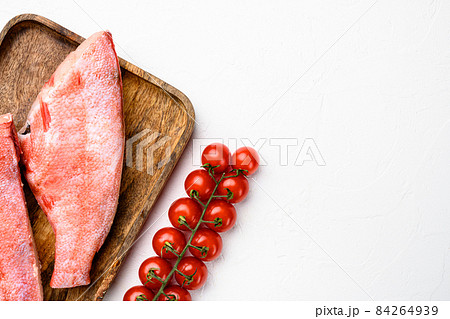 Raw red sea bass fish, on wooden serving board, on white stone table background, top view flat lay, with copy space for text Raw red sea bass fish, on wooden serving board, on white stone table background, top view flat lay, with copy space for text 84264939