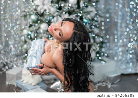 Beautiful nude woman posing against the backdrop of Christmas decorations. 84266288