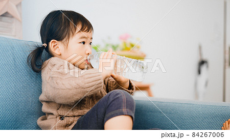 ペットボトルの水を飲む女の子	 84267006