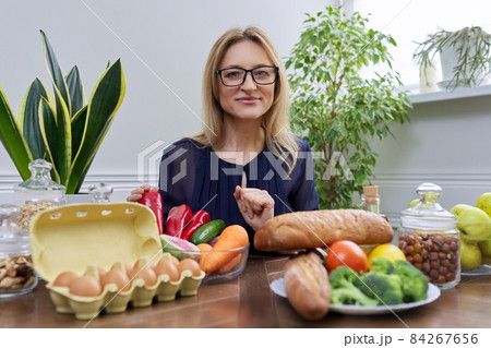 Smiling female nutritionist looking at camera with food set on table Smiling female nutritionist looking at camera with food set on table 84267656