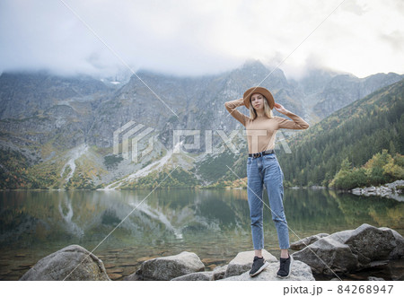 Young tourist woman in a hat with hands up on the top of the mountains 84268947