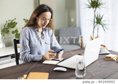 Freelancer young woman messaging with phone at home. 84269902