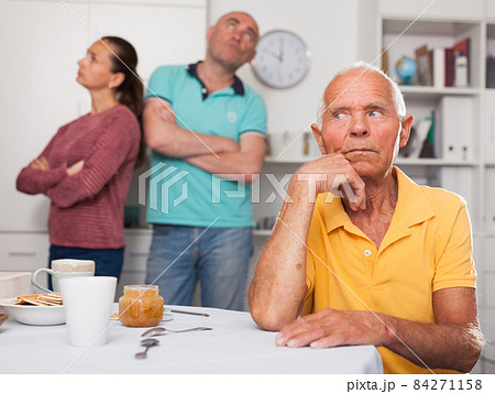 Elderly man sitting at table, unhappy family couple quarrelling 84271158