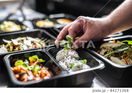 The chef in restaurant kitchen finishes the food ready for delivery in takeaway packages 84271368