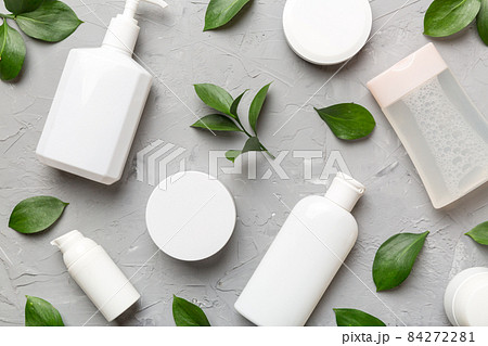 Organic cosmetic products with green leaves on cement background. Flat lay Organic cosmetic products with green leaves on cement background. Flat lay 84272281