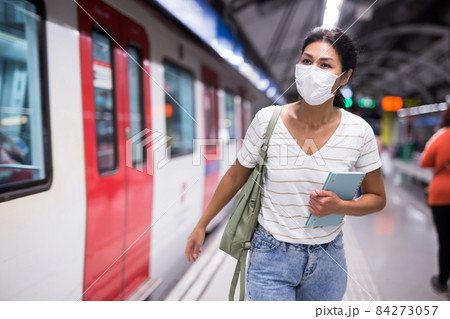 Woman in mask going along train in subway station 84273057