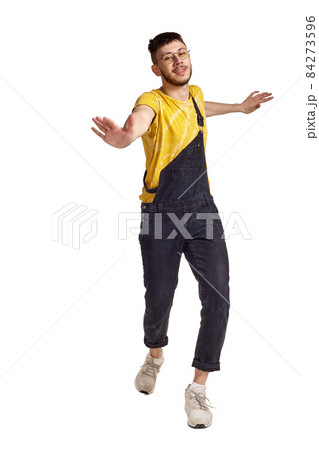 Full-length portrait of a funny guy dancing in studio isolated on white background. 84273596