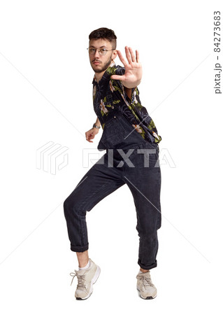 Full-length portrait of a funny guy dancing in studio isolated on white background. 84273683