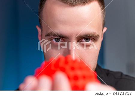 Portrait of a professional young caucasian male masseur in a dark uniform holding a massage ball in his hand for self-massage myofasceal 84273715