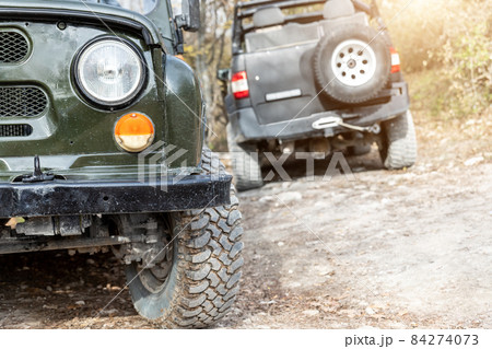 Pair of two old retro vintage 4x4 soviet suv vehicle on dirt gravel unpaved road in summer at sunset morning sun. Off road car mountain safari adventure nature trip journey concept. ATV rental . Pair of two old retro vintage 4x4 soviet suv vehicle on dirt gravel unpaved road in summer at sunset morning sun. Off road car mountain safari adventure nature trip journey concept. ATV rental . 84274073