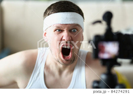 Man screaming on camera while performing exercise at home Man screaming on camera while performing exercise at home 84274291