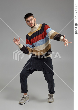 Full-length portrait of a funny guy dancing in studio on a gray background. 84274552