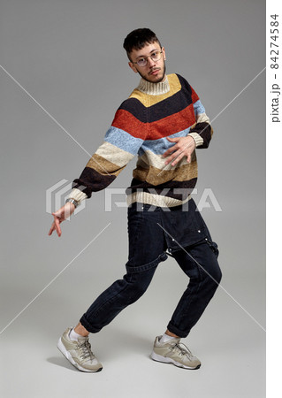 Full-length portrait of a funny guy dancing in studio on a gray background. 84274584