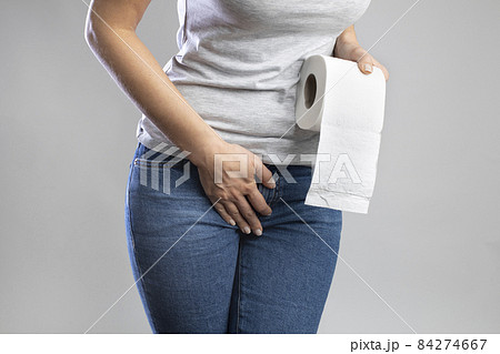 Woman hand holding her crotch lower abdomen and toilet paper roll. Disorder, diarrhea, incontinence 84274667