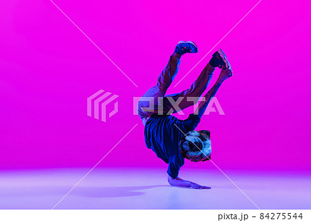 Young man, break dancing dancer headed of dog's head dancing isolated over bright magenta background at dance hall in neon light. 84275544