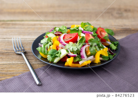 Plate of rainbow salad with different vegetables and herbs on black plate on wooden background 84276523