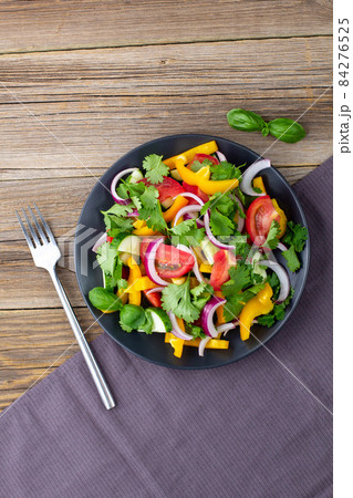 Plate of rainbow salad with different vegetables and herbs on black plate on wooden background Plate of rainbow salad with different vegetables and herbs on black plate on wooden background 84276525
