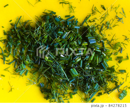 Finely chopped dill lies on a yellow cutting board. Finely chopped dill lies on a yellow cutting board. 84278215