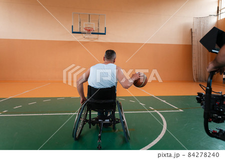a cameraman with professional equipment records a match of the national team in a wheelchair playing a match in the arena 84278240