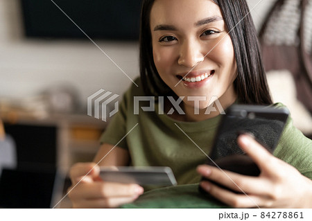 Young asian woman buying from online shop, using mobile phone and credit card, shopping from home Young asian woman buying from online shop, using mobile phone and credit card, shopping from home 84278861