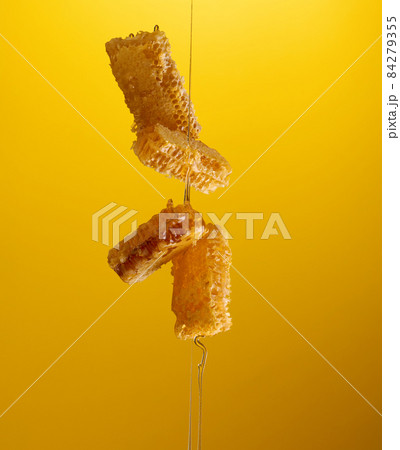 flowing honey over honeycomb on yellow background 84279355