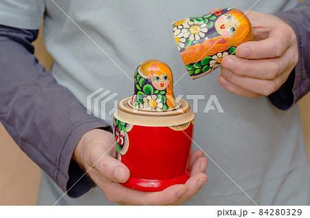 An adult male holding a wooden matryoshka doll. An uncovered tra An adult male holding a wooden matryoshka doll. An uncovered tra 84280329