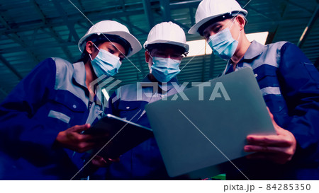 Asian team of engineers wearing medical face masks working together in factory under COVID-19 situation Asian team of engineers wearing medical face masks working together in factory under COVID-19 situation 84285350