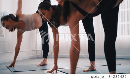 Group of Asian women stretching in yoga class. Group of girls doing Pilates exercises at the gym. 84285422