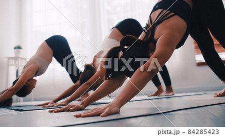 Group of Asian women stretching in yoga class. Group of girls doing Pilates exercises at the gym. 84285423