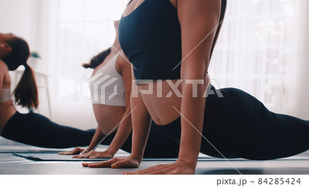 Group of Asian women stretching in yoga class. Group of girls doing Pilates exercises at the gym. 84285424