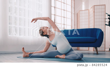 Asian pregnant woman doing yoga exercises at home. 84285524