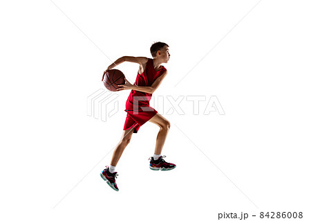 Full-length portrait of teenager, boy in red uniform playeing, training basketball isolated over white background. Active game Full-length portrait of teenager, boy in red uniform playeing, training basketball isolated over white background. Active game 84286008