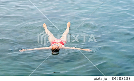 female in glasses lies a star on the sea, trains to maintain balance on the water, relaxation 84288183