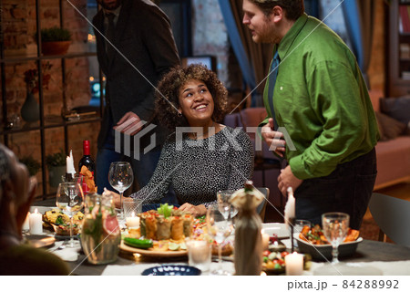 African happy woman talking to the man while sitting at dining table, they visiting dinner party with friends 84288992