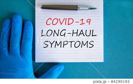 COVID-19 long-haul covid symptoms symbol. White card with words Covid-19 long-haul symptoms. Doctor hand, pen, blue background, copy space. Medical, COVID-19 long-haul covid symptoms concept. 84290193