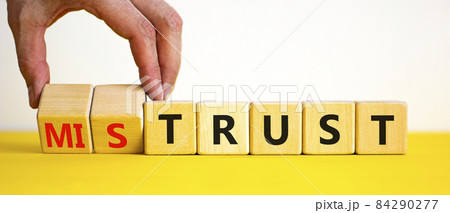 Mistrust or trust symbol. Businessman turns wooden cubes, changes words 'mistrust' to 'trust'. Beautiful yellow table, white background. Business and mistrust or trust concept, copy space. 84290277