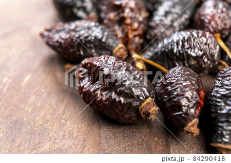 Dried wrinkled briar berries. Dry rose hips. Dog-rose fruits on a rustic wooden surface. Macro. Healthy food concept 84290418