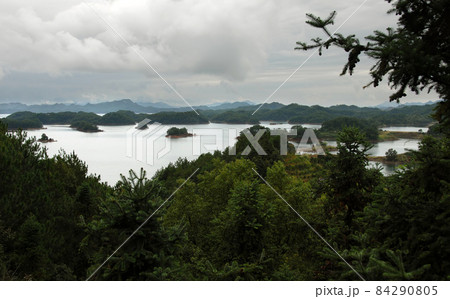 Qiandao Hu, Zhejiang Province, China: View of the lake and islands under a dramatic sky with foreground forest. Qiandao Hu translates as Thousand Island Lake and is a reservoir near Hangzhou. Qiandao Hu, Zhejiang Province, China: View of the lake and islands under a dramatic sky with foreground forest. Qiandao Hu translates as Thousand Island Lake and is a reservoir near Hangzhou. 84290805