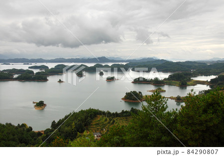 Qiandao Hu, Zhejiang Province, China: View of the lake and islands under a dramatic sky with foreground forest. Qiandao Hu translates as Thousand Island Lake and is a reservoir near Hangzhou. Qiandao Hu, Zhejiang Province, China: View of the lake and islands under a dramatic sky with foreground forest. Qiandao Hu translates as Thousand Island Lake and is a reservoir near Hangzhou. 84290807