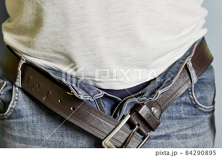 A man with unbuckled belt. Cropped shot of a man unbuckled his belt and unbuttoned jeans 84290895