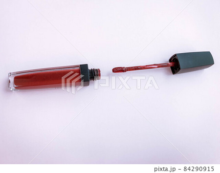 lipstick on a white-pink bright matte background. lipstick in a trendy, stylish red shade. lipstick with a soft brush, lip makeup, matte gloss with hydration 84290915