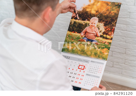 man holds a calendar with a photo of a child. printed products. man holds a calendar with a photo of a child. printed products. 84291120