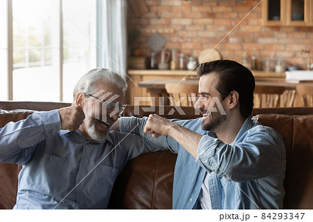 Laughing old father bumping fists with adult son 84293347
