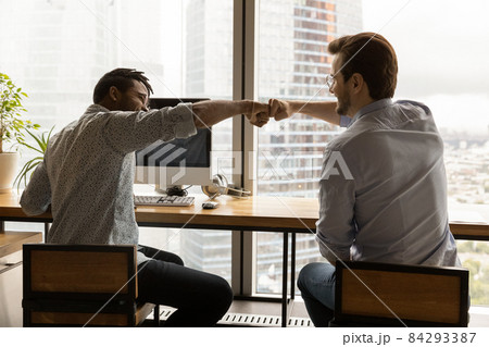 Happy two mixed race male colleagues bumping fists. 84293387