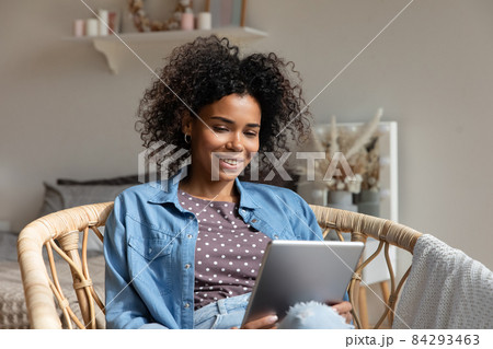Happy young woman reading book, ebook on tablet at home Happy young woman reading book, ebook on tablet at home 84293463