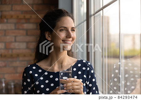 Dreamy young woman begin day from glass of pure water 84293474