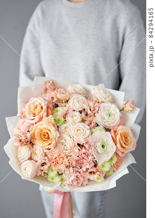 Flower arrangement in Wicker basket. Beautiful bouquet of mixed flowers in woman hand. Handsome fresh bouquet. Small flower shop and Flowers delivery. 84294165