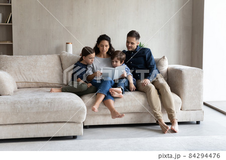 Couple with children sit on sofa enjoy fascinating fairytale book Couple with children sit on sofa enjoy fascinating fairytale book 84294476